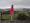portraitfoto von frau in pinker jacke, hügelige landschaft im hintergrund