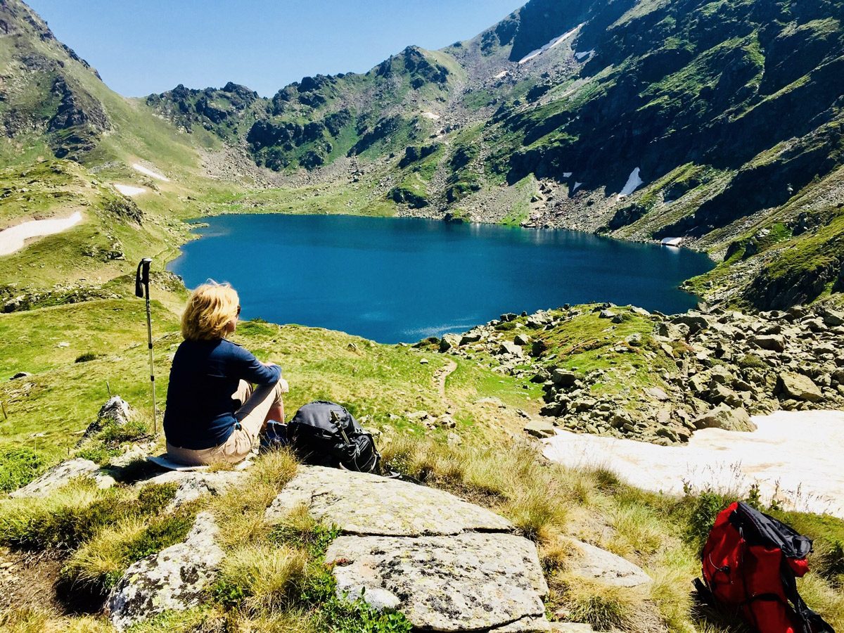 blauer Bergsee mit Wandererin im Vordergrund