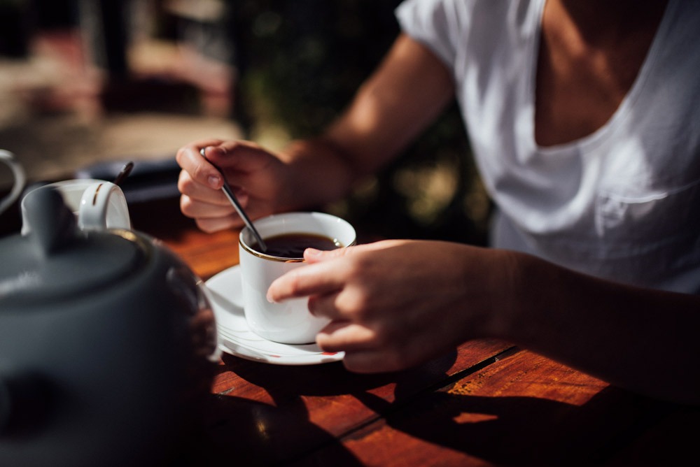 Nahaufnahme von händen einer frau, die in einer tasse tee rührt