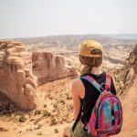 Eine Frau sitzt auf dem Boden und genießt die sagenhafte Aussicht im Arches Nationalpark. © Strauss Western