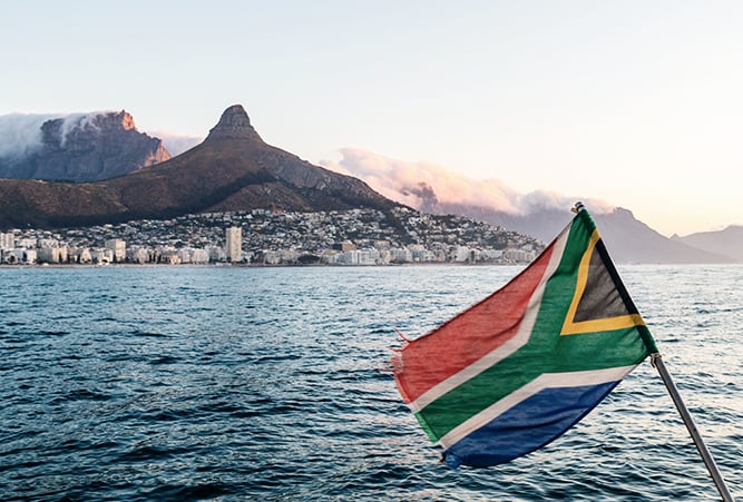 Die südafrikanische Flagge weht auf einem Boot vor dem Tafelberg