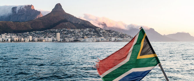 Die südafrikanische Flagge weht auf einem Boot vor dem Tafelberg