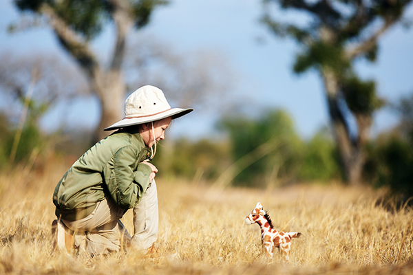 Ein Kind in Safari-Outfit mit einer Plüschgiraffe