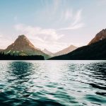 Tiefes, hellblaues Wasser mit gigantischer Aussicht auf Berge, Glacier Nationalpark. © Tevin Trinh