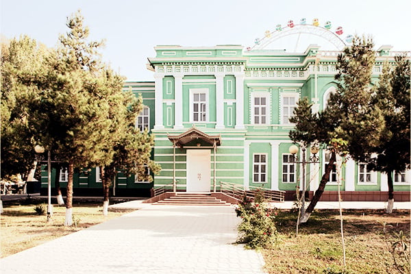 Grüne Fassade des Gebäudes des Militärgouverneurs vor Riesenrad in Fergana in Usbekistan