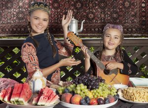 Usbekische Mädchen in traditioneller Kleidung am gedeckten Tisch