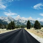 Einsame Straße, die schneebedeckten Berge des Grand Teton Nationalparks im Hintergrund. © Victoria Dihua