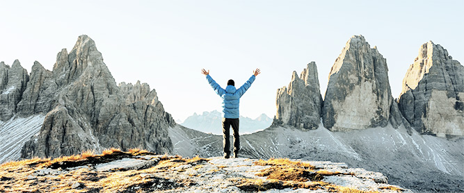 Wanderer springt vor den Dolomiten