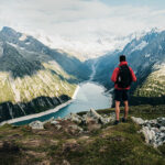 Wanderer mit roter Jacke blickt auf Berge und Seen im Zilltertal in den Alpen
