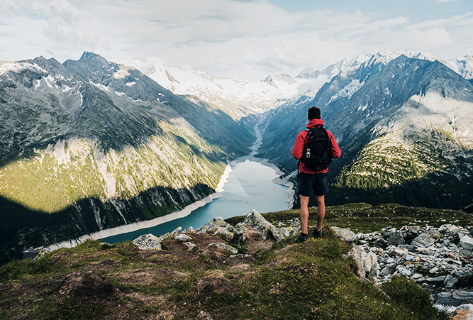 Wanderer mit roter Jacke blickt auf Berge und Seen im Zilltertal in den Alpen