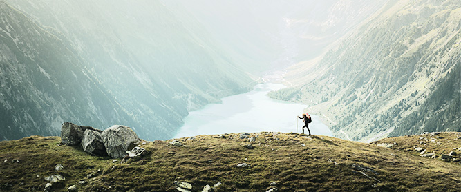 Wanderer vor einem Panorama aus einem See und Berge links und rechts