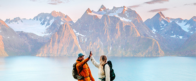 Mann und Frau klatschen sich vor beeindruckender Bergkulisse ab